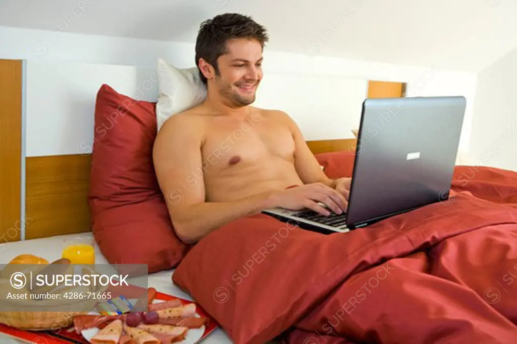 man working with a laptop in the bedroom