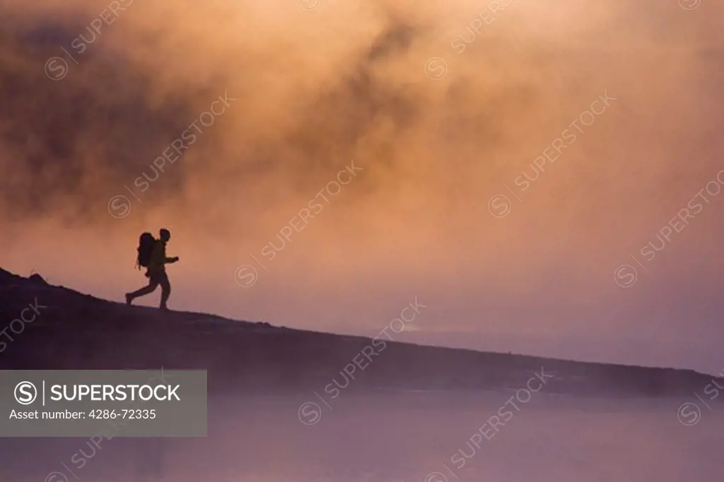 A man hiking along the shore of a misty lake at dawn near Truckee California