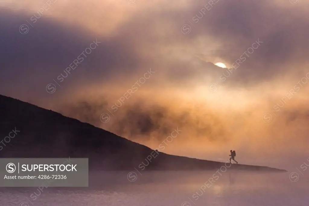 A man hiking along the shore of a misty lake at dawn near Truckee California