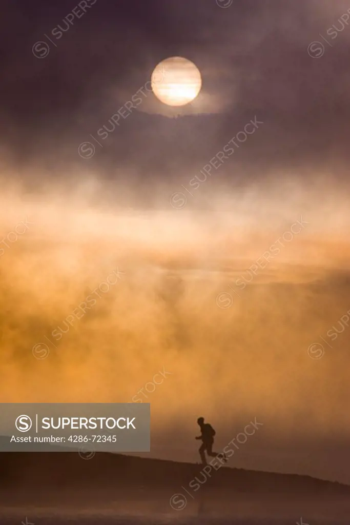 A man running along the shore of a misty lake at dawn near Truckee California