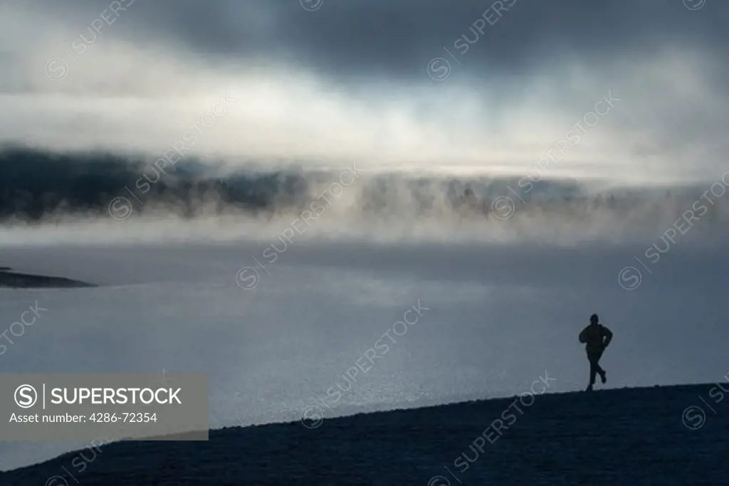 A man running along the shore of a misty lake at dawn near Truckee California