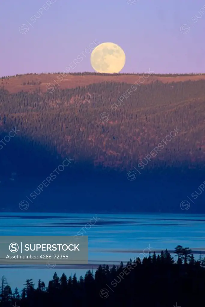 The full moon rising over LakeTahoe at sunset with alpenglow at Lake Tahoe California