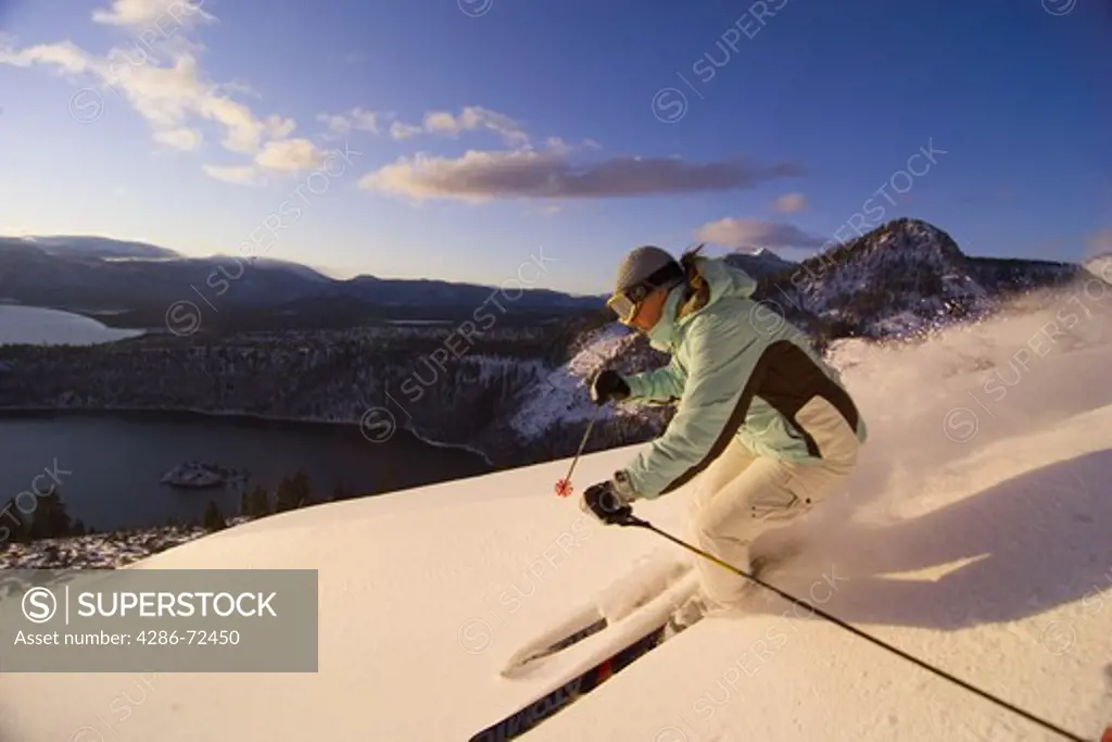 A woman skiing powder snow at sunrise above Emerald Bay on Lake Tahoe in California