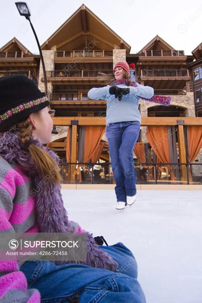 A young girl watching a woman skate at Northstar ski resort near Lake Tahoe in California