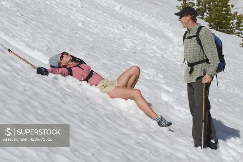 A woman laughing after having fallen in the snow with her male friend on Donner Summit in the Sierra mountains of California