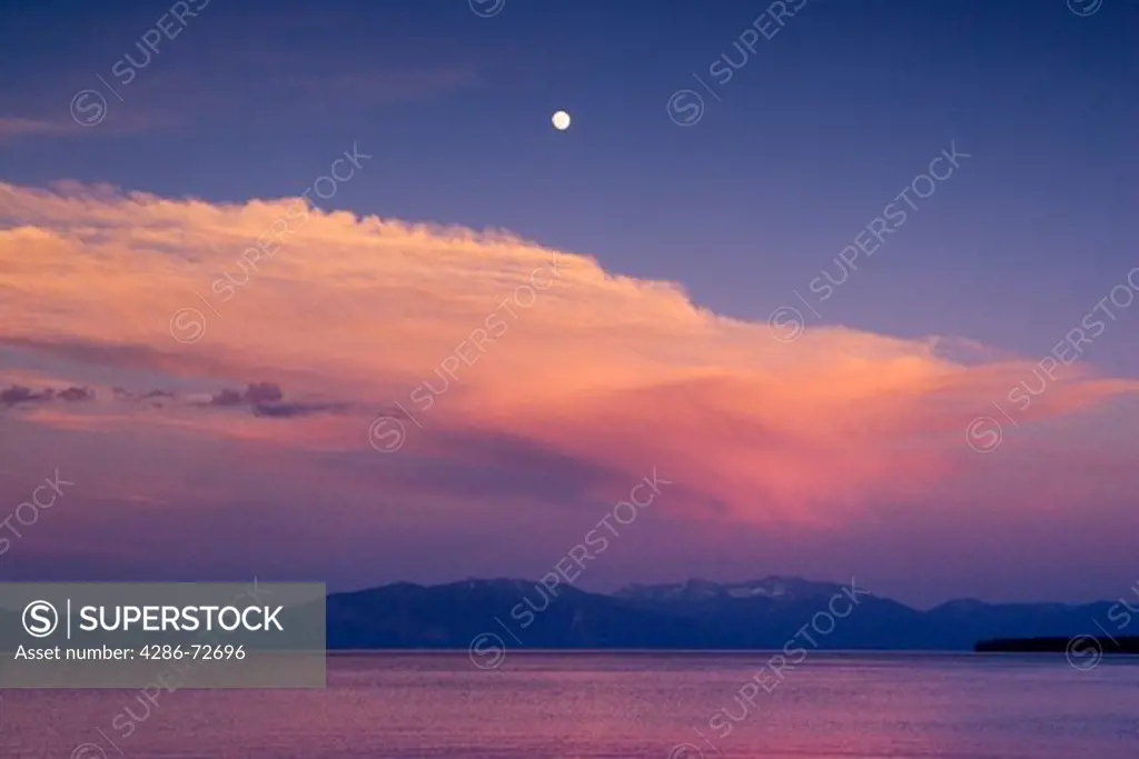 The full moon and a thunderhead cloud over Lake Tahoe, California at sunset