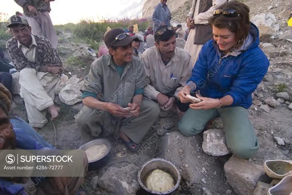  A caucasian woman making chapati bread with some Balti men in Pakistan