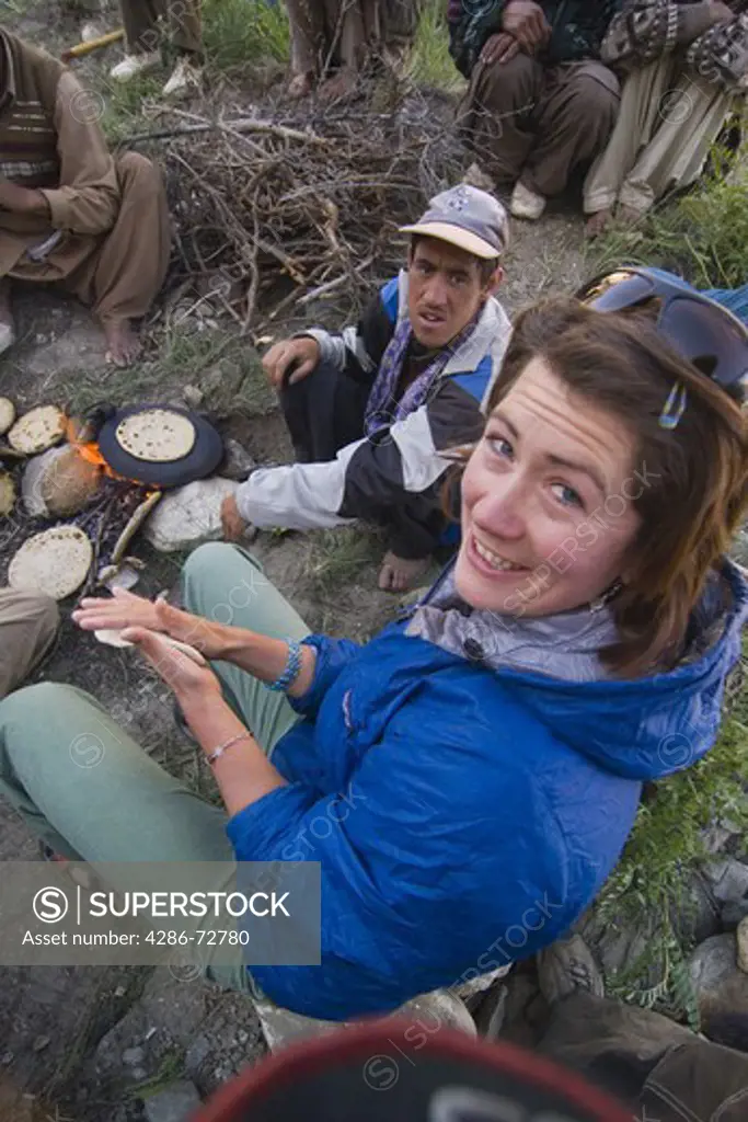  A caucasian woman making chapati bread with some Balti men in Pakistan