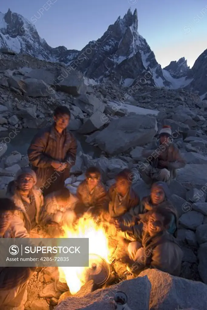 Balti porters around a camp fire at dusk on the Biafo glacier in Baltistan in Pakistan