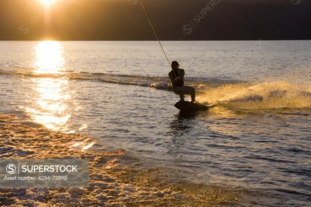  A man wakeboarding at sunrise on Lake Tahoe in California
