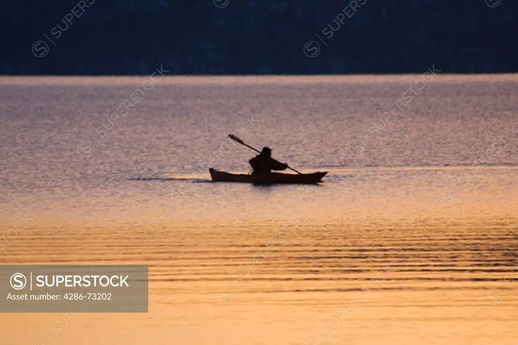 A man sea kayaking on Lake Tahoe California at sunrise