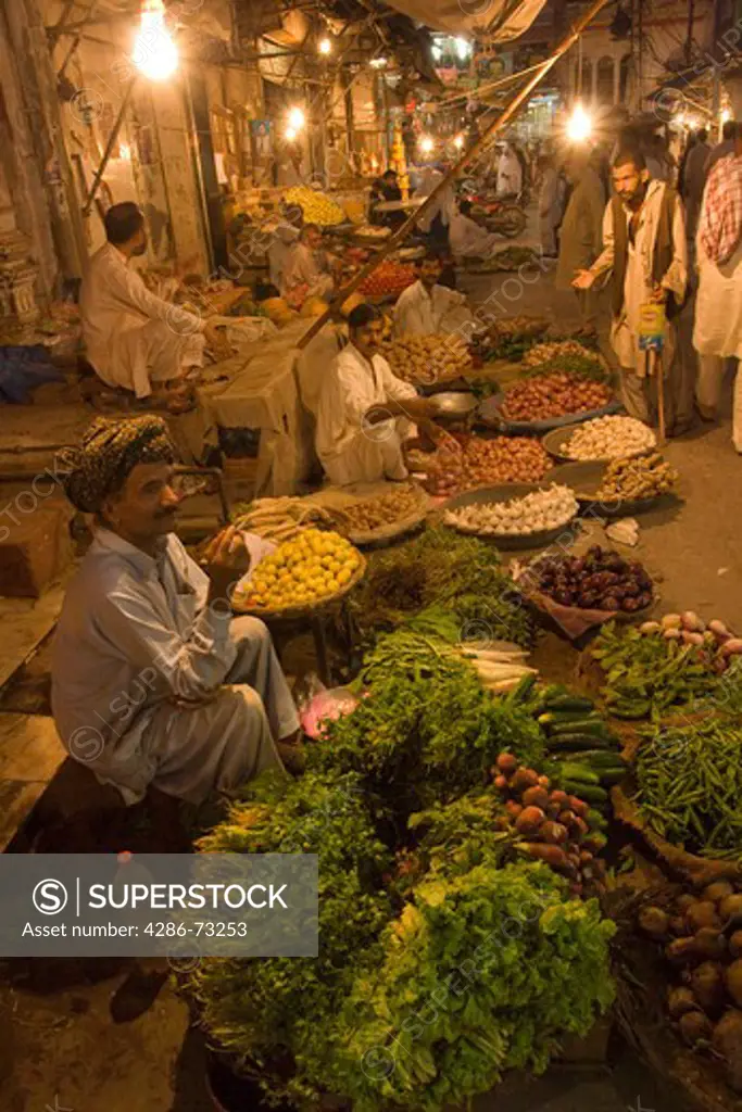 A street vendor smoking a cigarette and selling vegetables at night in the old bazaar in Rawalpindi in Pakistan