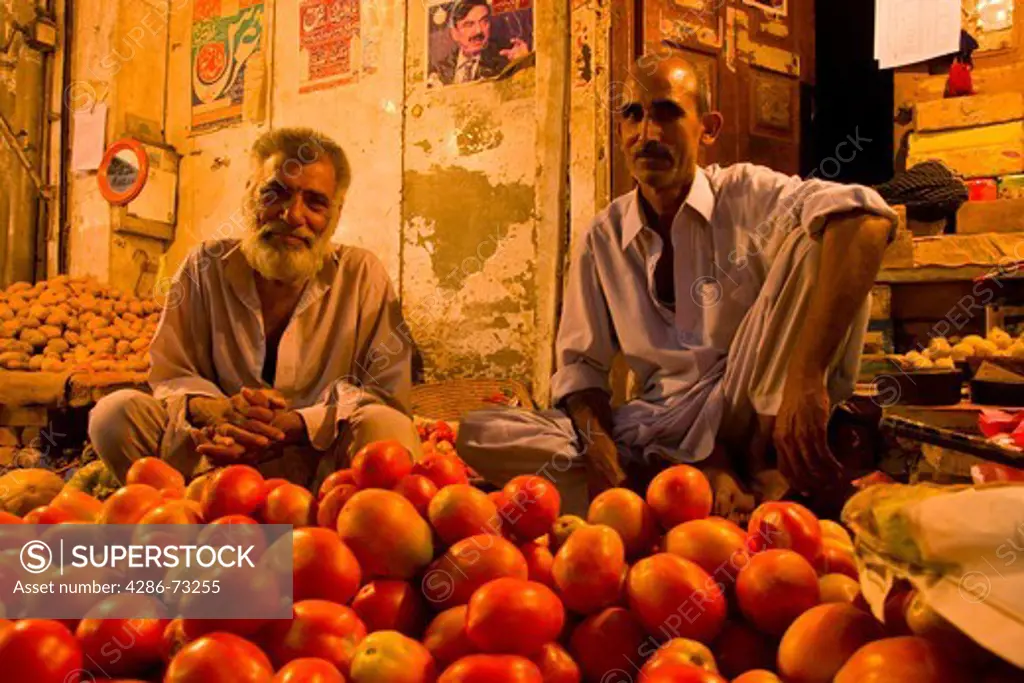 Two shopkeepers selling tomatoes at night in the old Bazaar in Rawalpindi in Pakistan
