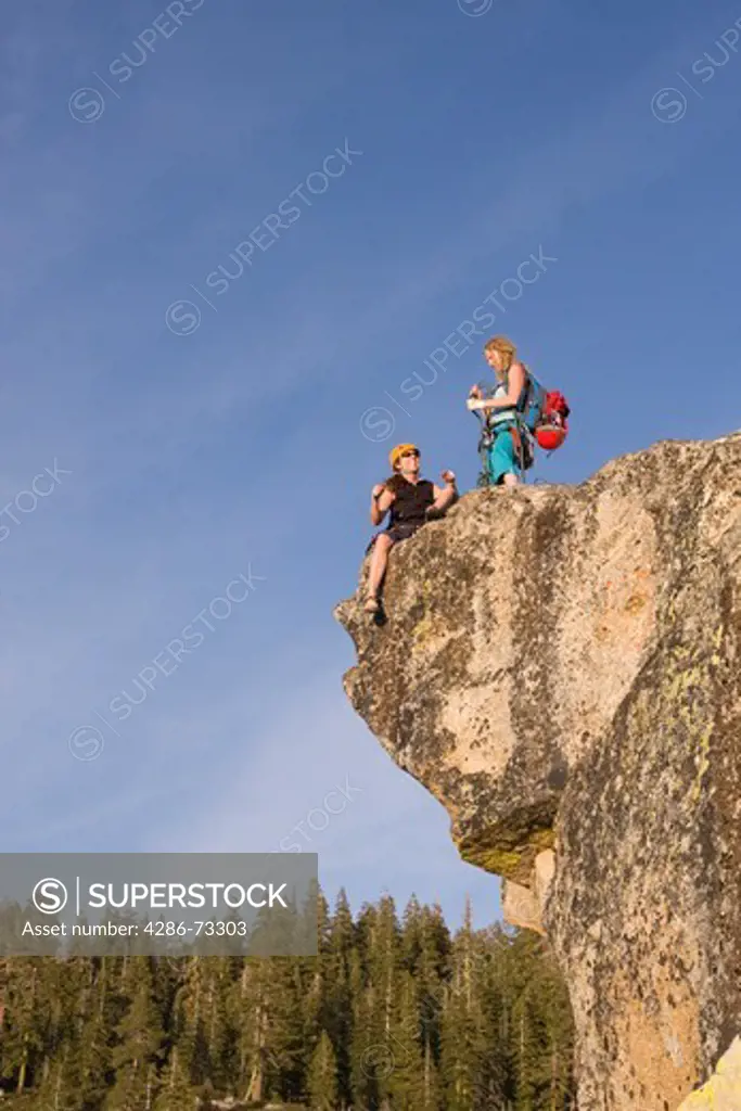  Two female rock climbers on an overhanging cliff at Taft Point at sunset in Yosemite National Park in California after havng completed a climb