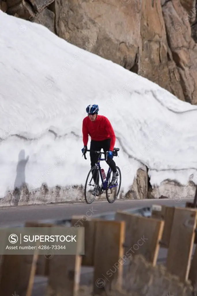  A man climbing uphill on a bicyle in winter on Donner Summit in California
