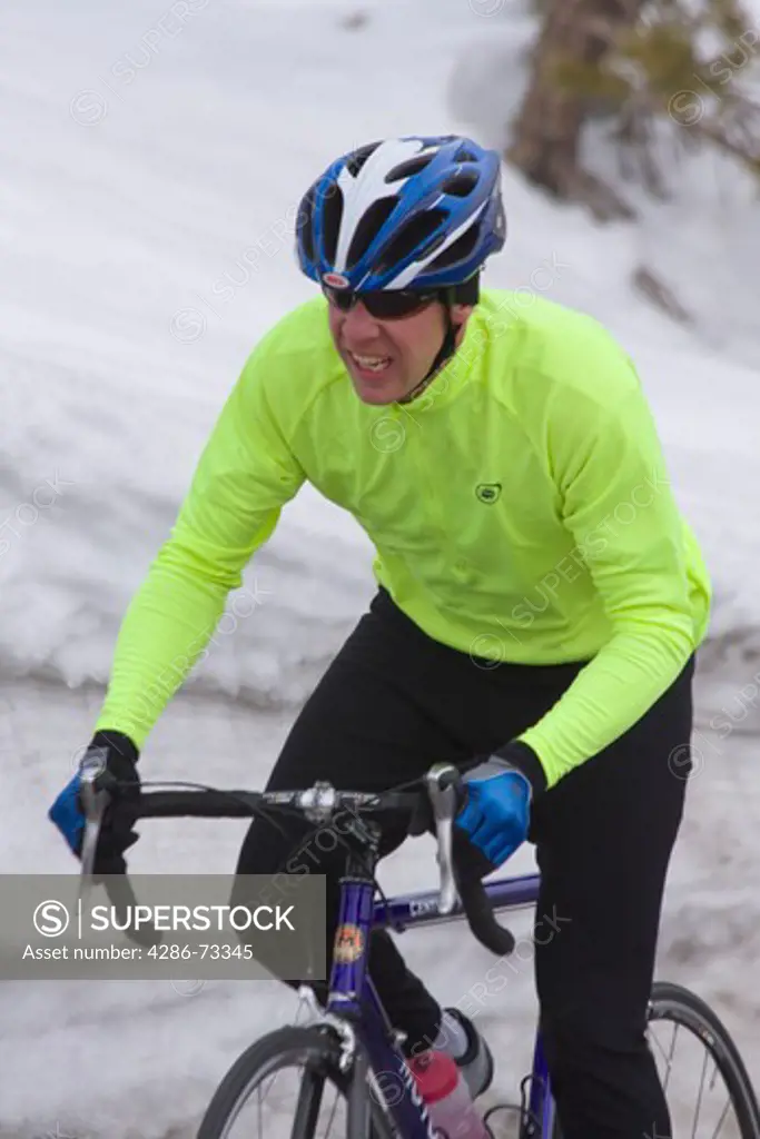  A man climbing uphill on a bicyle in winter on Donner Summit in California