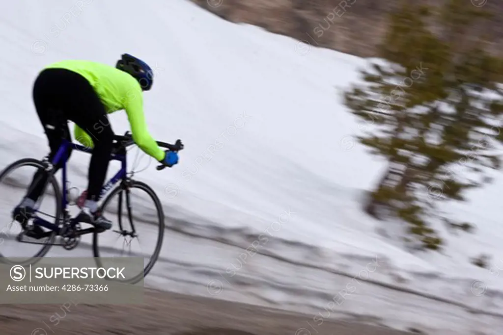  A blurry photo of a man riding a bicycle downhill at high speed on old highway 40 on Donner Summit near Truckee California