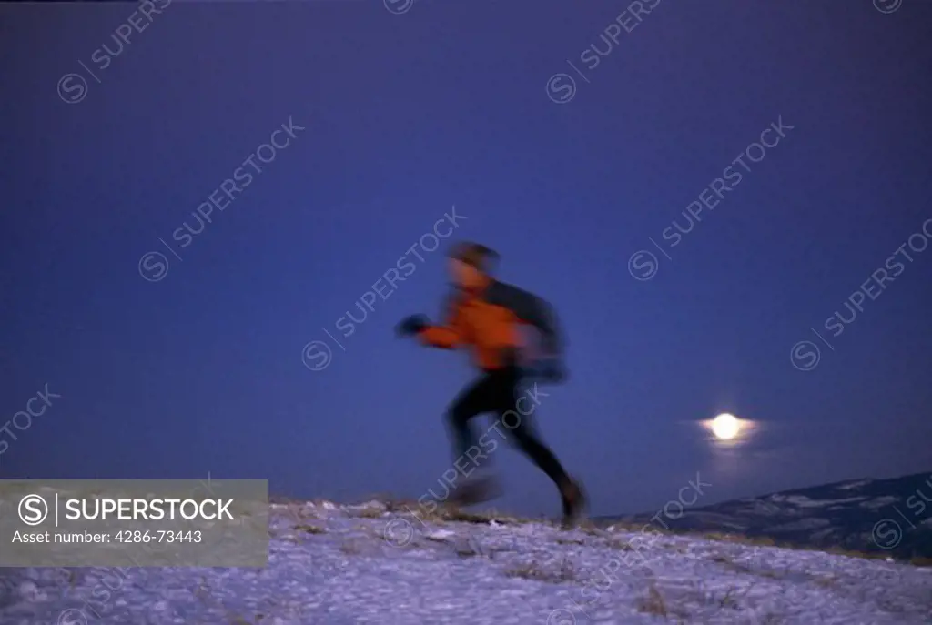 Young man running at night on Mount Judah in the Sierra mountains near Truckee, California, USA