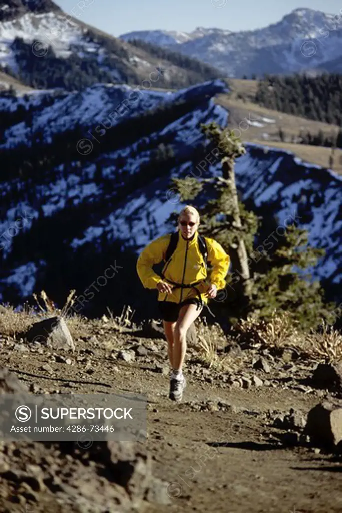 Young woman running on trail on Mount Judah in the Sierra mountains near Truckee, California, USA