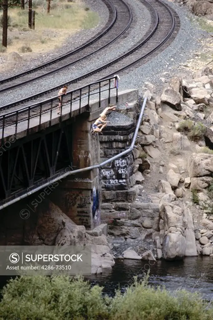 People in midair jumping off bridge into the Truckee River, California, USA