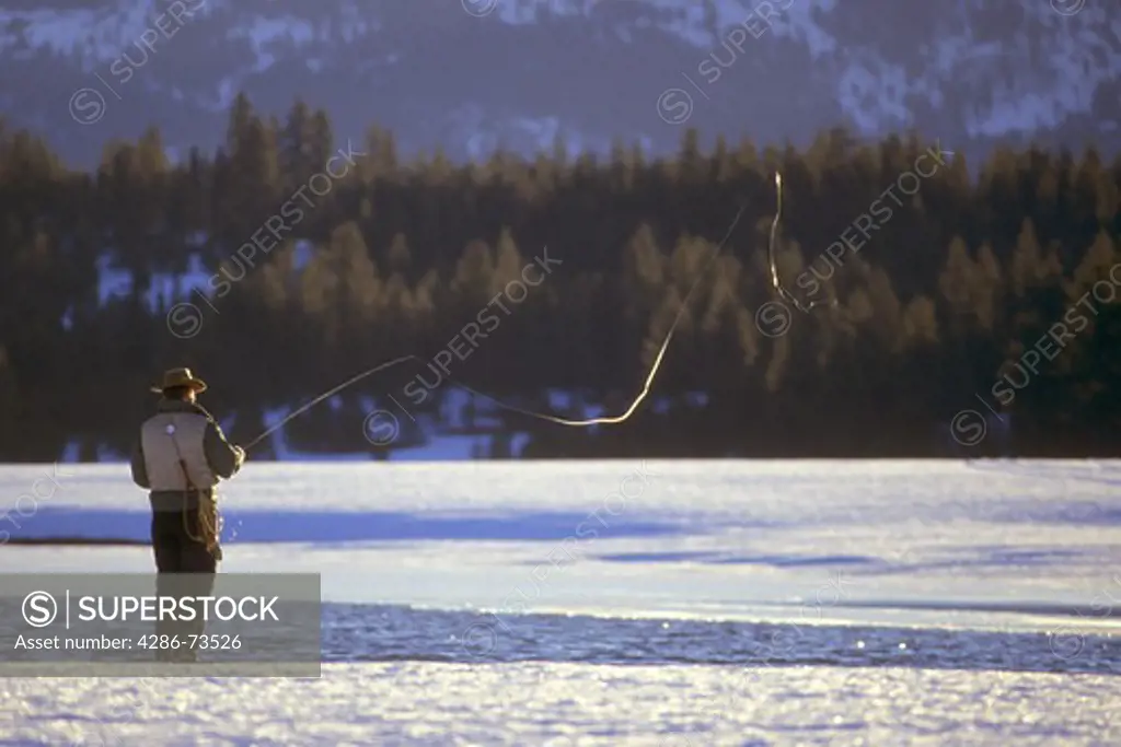 Rear view of man ice fishing at Stampede Reservoir near Truckee, California, USA