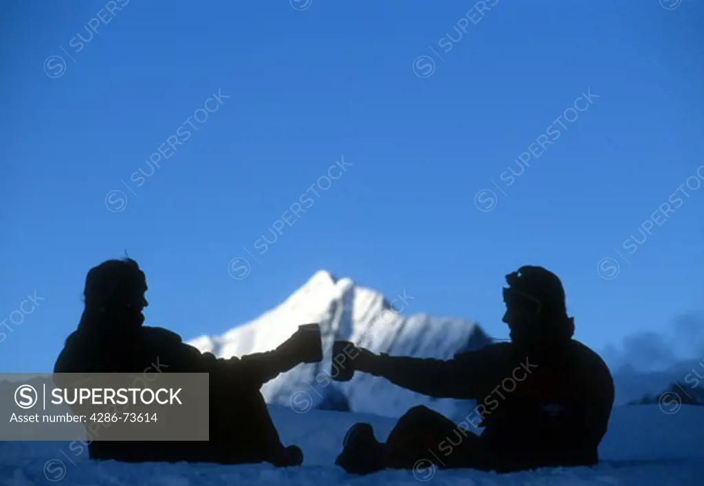 Silhouette of couple toasting drinks at Ruth Gorge, Denali National Park, Alaska, USA