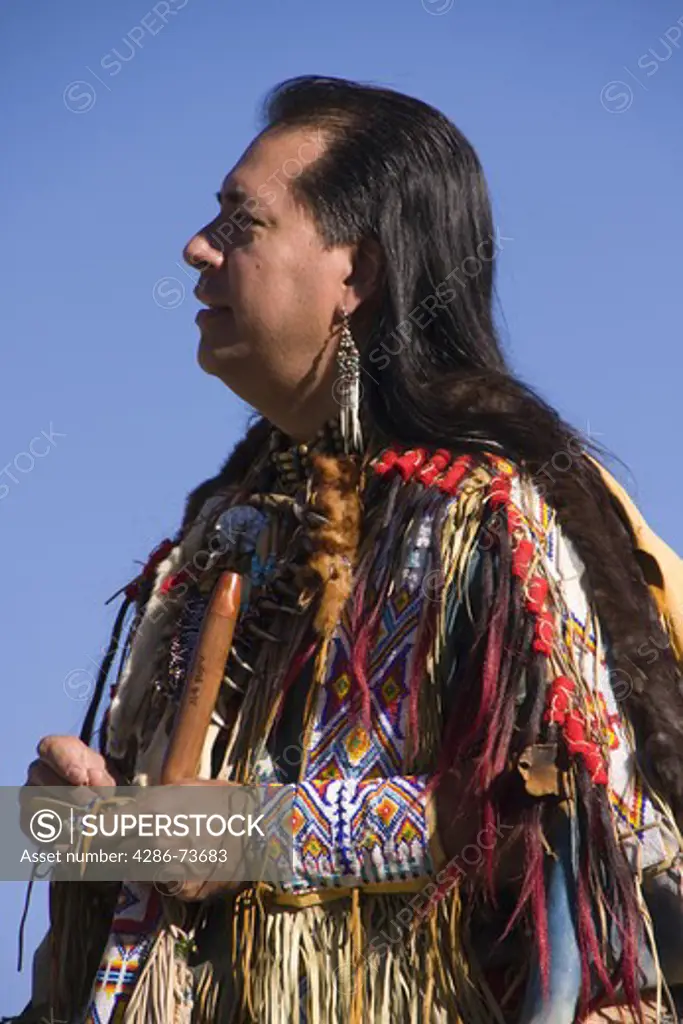 A Lakota Native American Indian warrior in full traditional dress standing outdoors on a rock on Donner Summit near Truckee in California