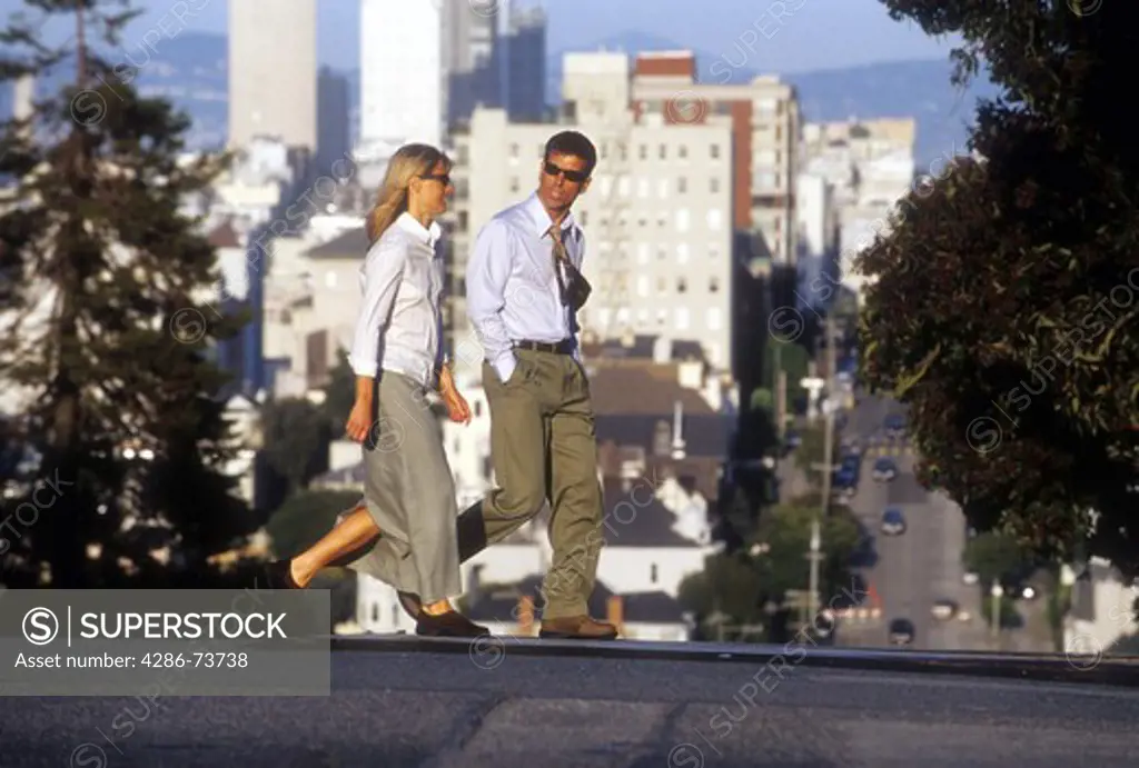 A business man and woman walking across a street in san Francisco