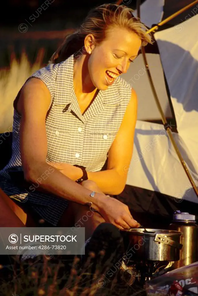 Young woman cooking at campsite, Donner Summit near Truckee, California, USA 