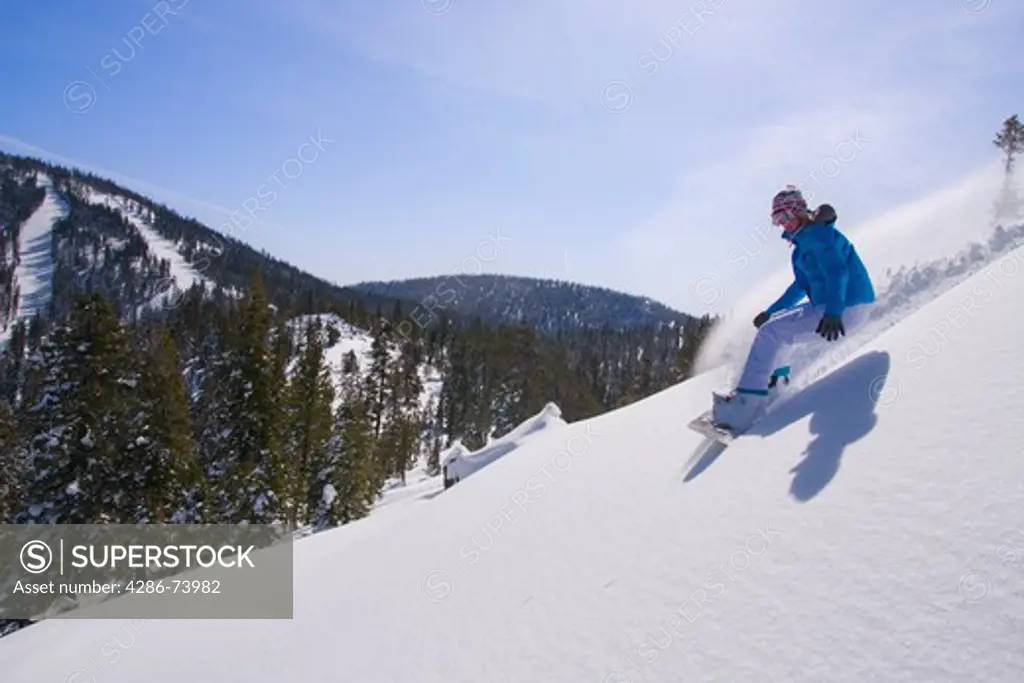 A woman snowboarding on a sunny day in fresh powder snow at Northstar near Lake Tahoe in California