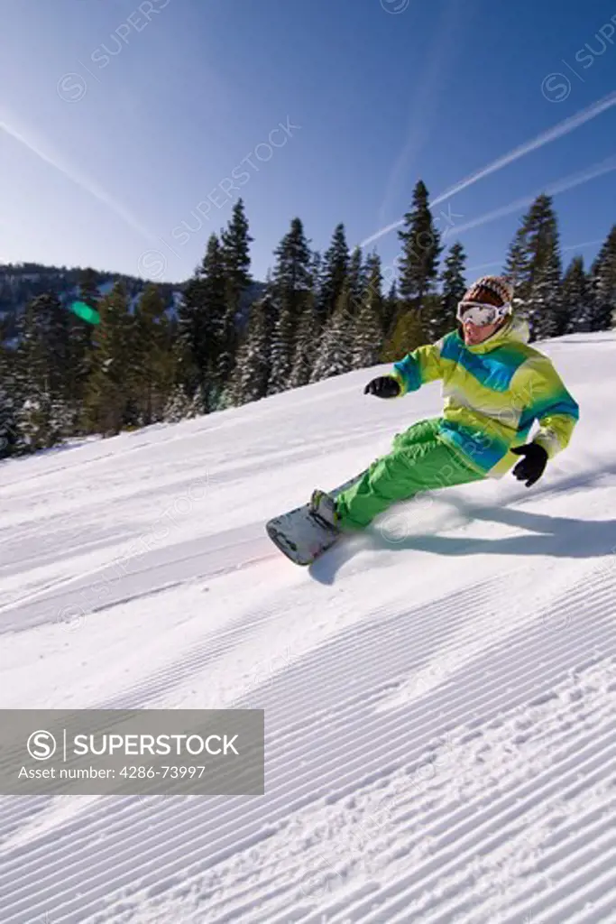 A man snowboarding on a freshly groomed slope on a sunny day at Northstar near Lake Tahoe in California