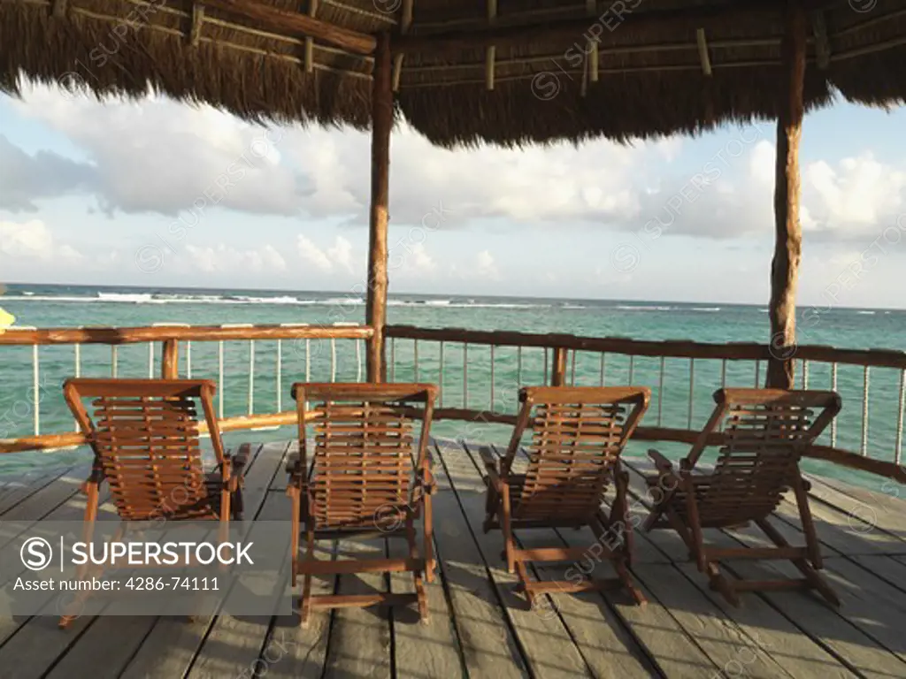 Mexico Quintana Roo Yucatan Peninsula Akumal Mayan Riviera,deck chairs facing the sea from under a palapa