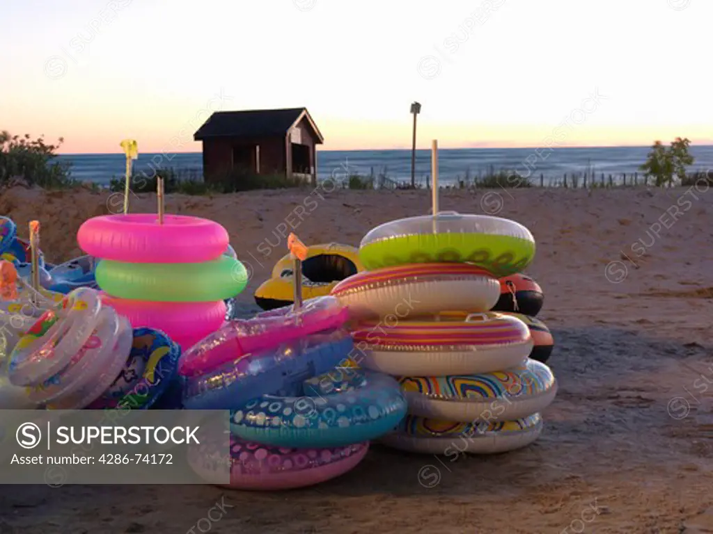 Canada,Ontario,Sauble Beach, beach floatation devices at a beach stand illuminated at dusk with beach in background