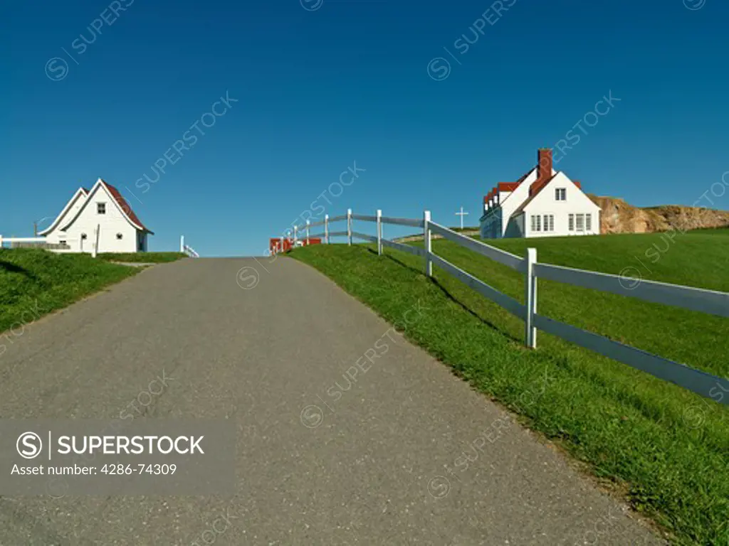 Canada,Quebec,Gaspesie,Perce,road lined with white fence and white clapboard homes in the town of Perce