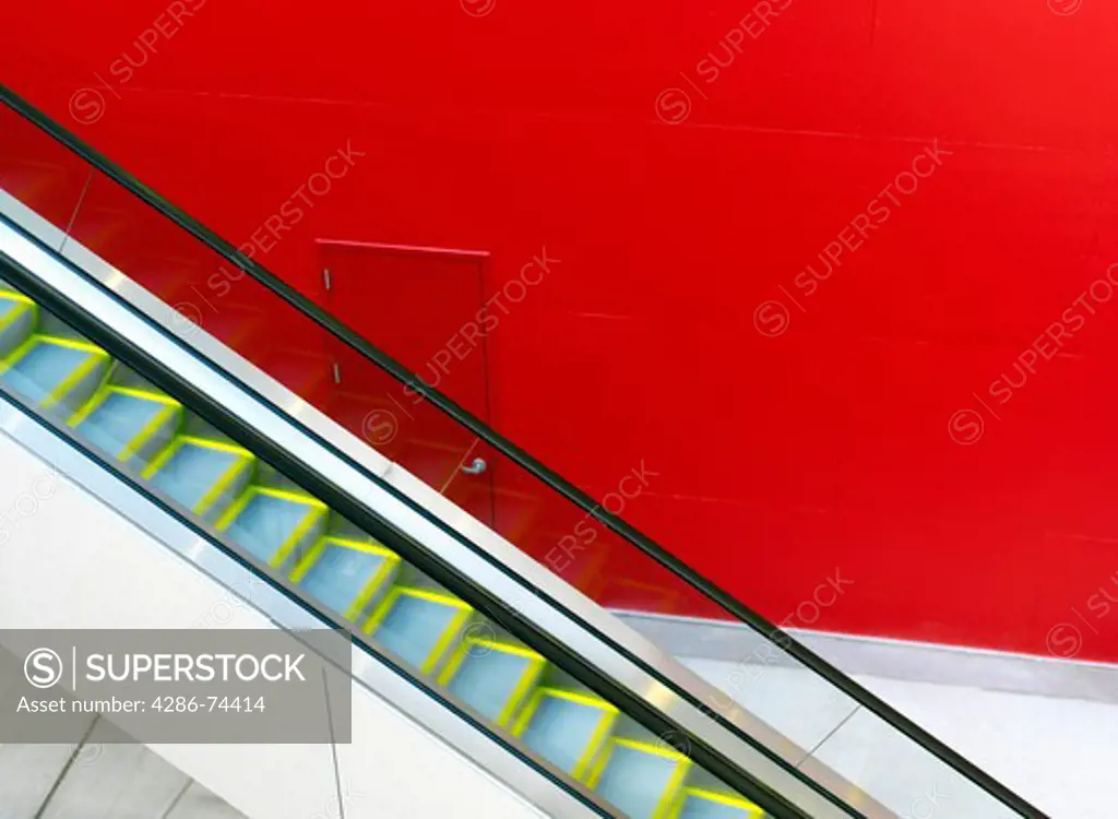 escalator against a red painted wall