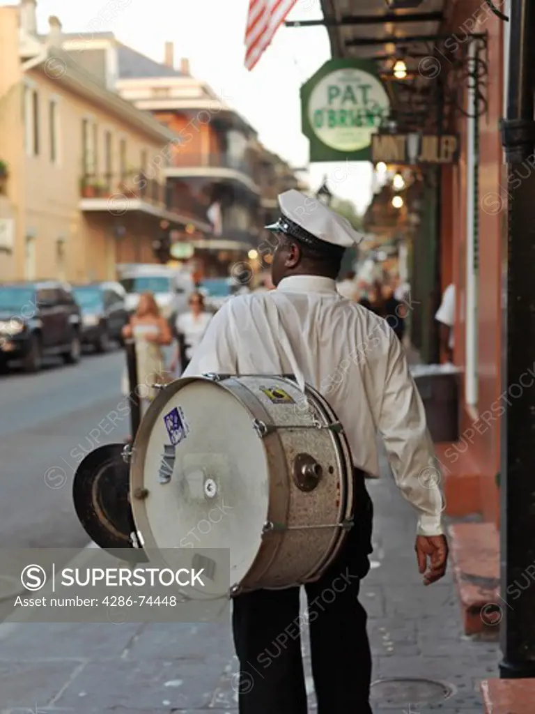 USA,Louisiana,New Orleans,French Quarter,second line parade musician walking along street with drum