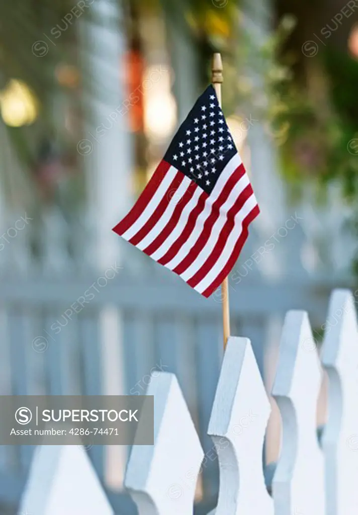 Close up of a small U.S. Flag on a white picket fence