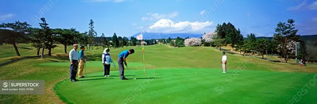 Japanese men playing golf  below Mount Fujiyama on Honshu Island