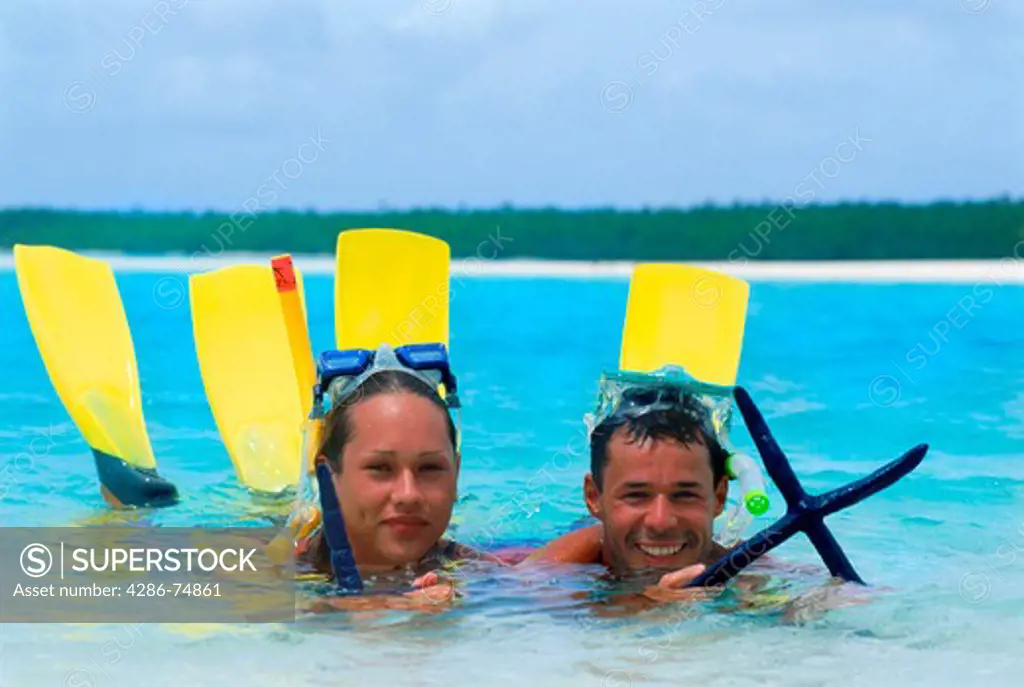 Couple with starfish off One Foot Island in Aitutaki lagoon in Cook Islands