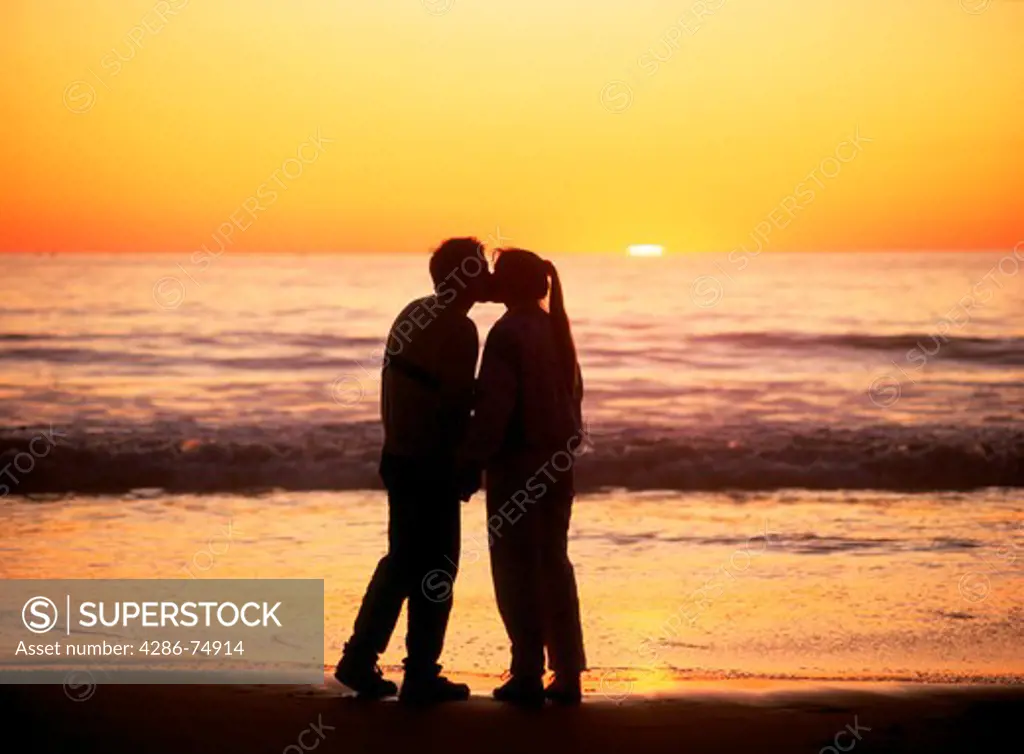 Couple on beach kissing at sunset