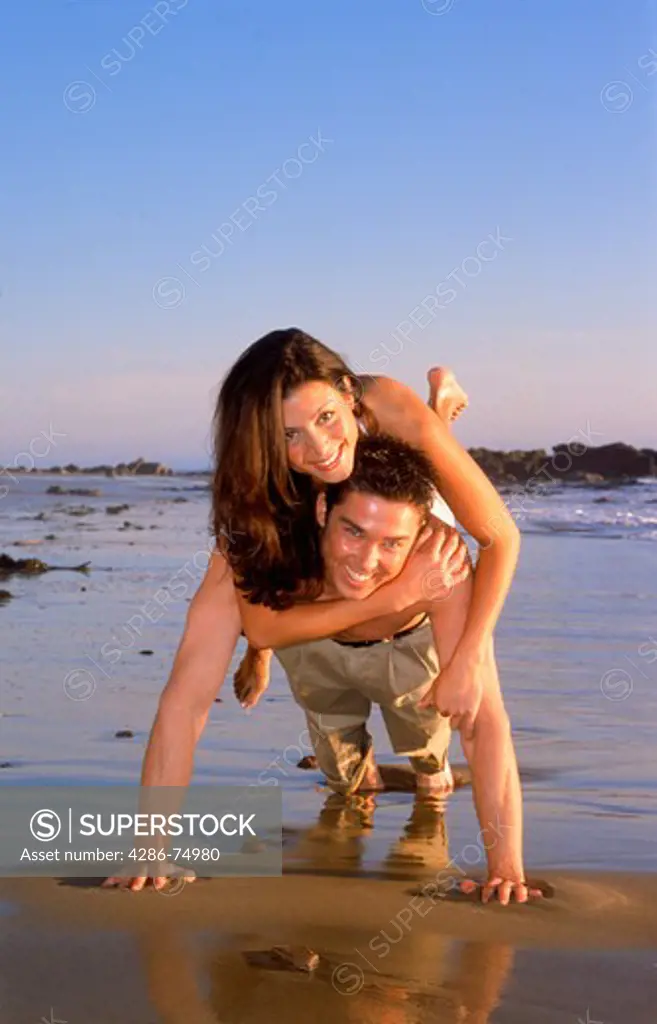 Couple 20-30 years playing on wet sandy shore in Southern California
