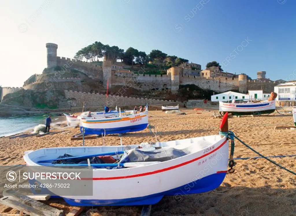 Fishing boats below castle at Tossa De Mar in Girona Province of Spain at sunrise