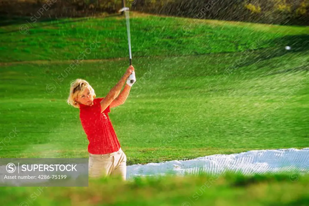 Woman golfer blasting out of sand trap