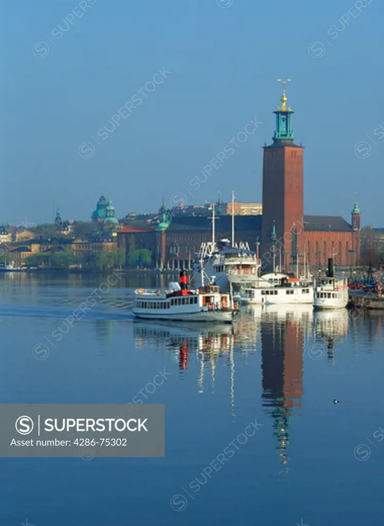 Town Hall reflecting off Riddarfjarden waters with ferryboats in Stockholm