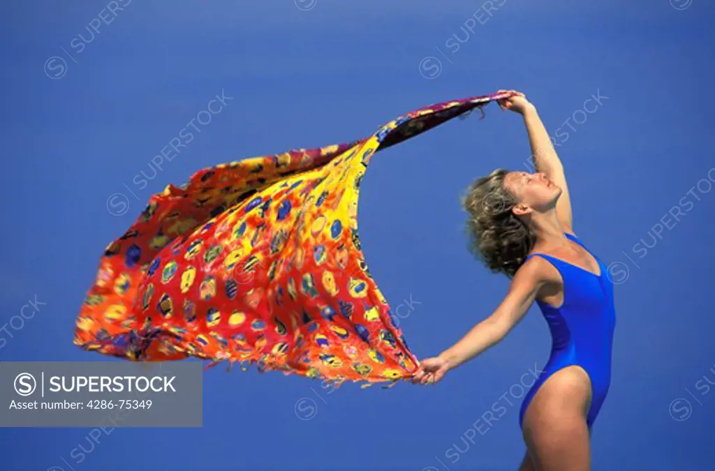 Woman holding colorful scarf feeling the wind and sun