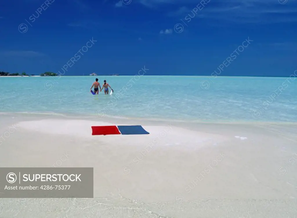 Couple leaving towels on tiny sandbar in Maldive Islands