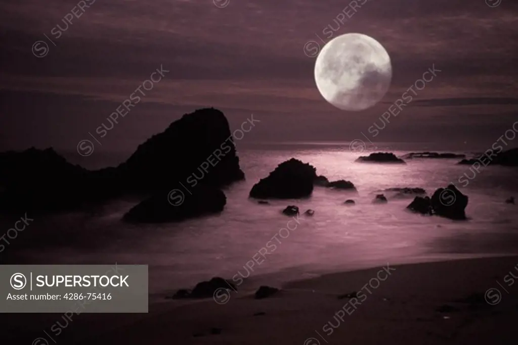 Moonset over rocky shore in Laguna Beach California