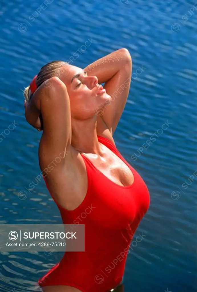 Blond woman of Brazilian Swedish ethnicity bathing in lake in red swimsuit