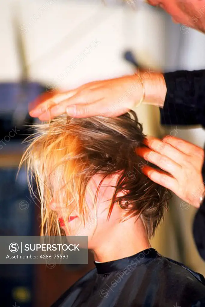 Woman getting hair cut, shampoo and permanent by  beautician at hair salon
