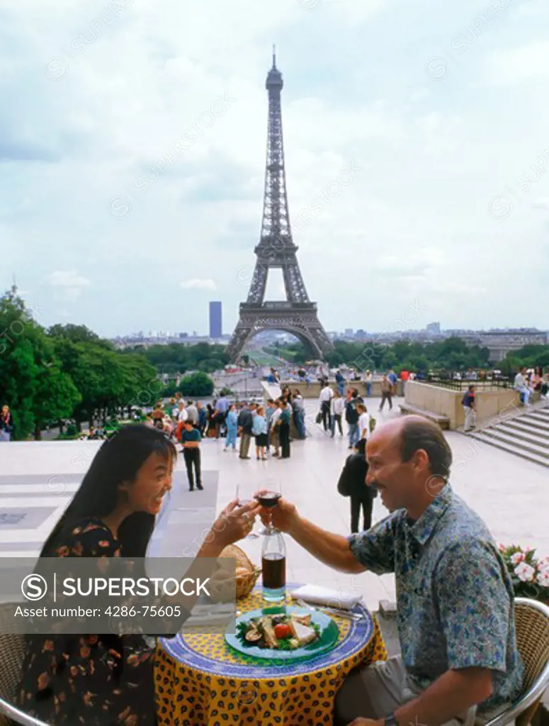 French wine, cheese, bread and tablecloth at Trocadero restaurant with Eiffel Tower and passing tourists
